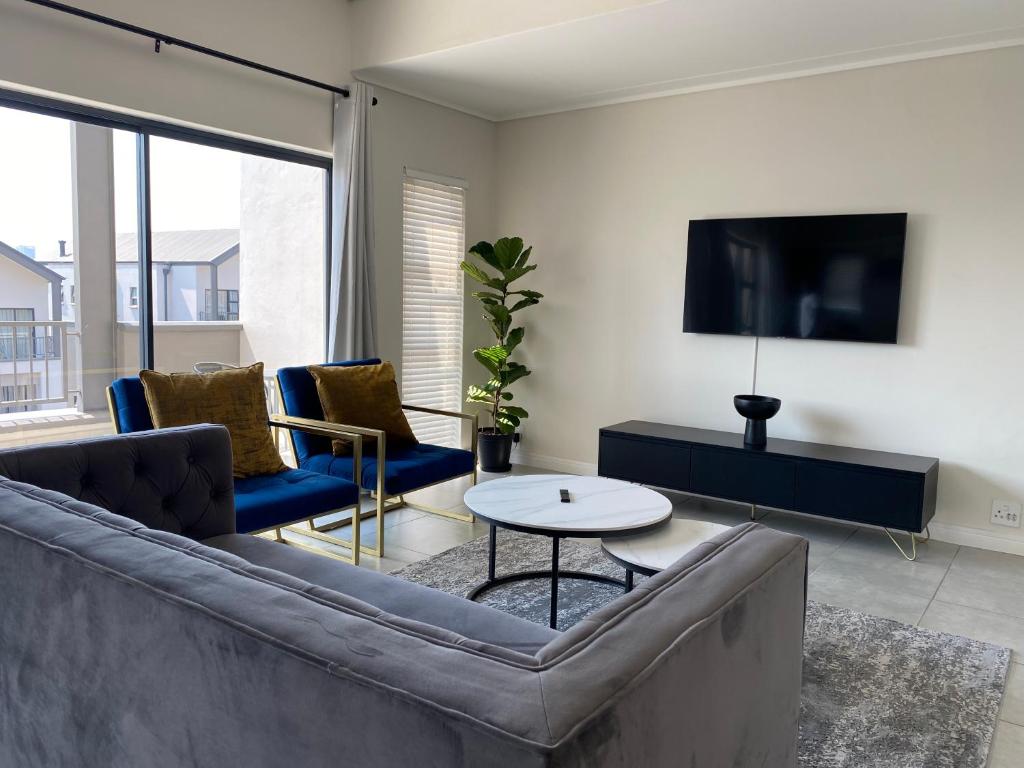 a living room with a couch and a tv at Penthouse in Waterfall with backup power in Midrand
