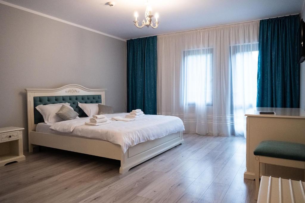 a bedroom with a white bed and blue curtains at Perla Dacilor in Grădiştea de Munte
