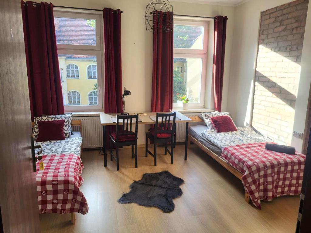 a room with two beds and a table and two windows at Lemuria Hostel Wrocławska centrum in Legnica