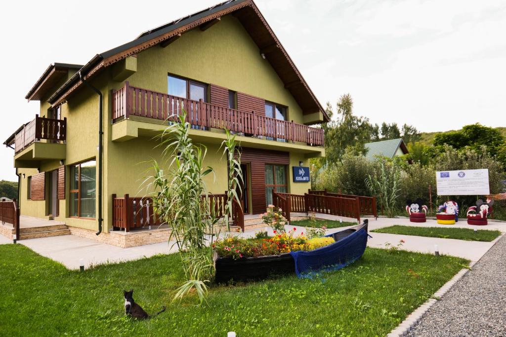 ein Haus mit einem Hund, der im Gras davor sitzt in der Unterkunft Agropensiunea Acasa La Matei in Luncaviţa