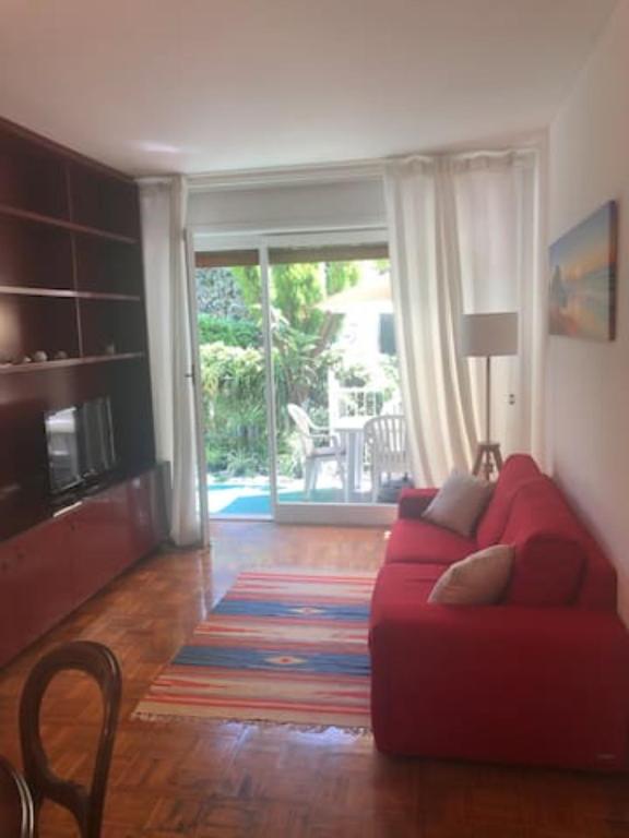 een woonkamer met een rode bank en een glazen schuifdeur bij GUISCI BEACH HOUSE - 10 Passi dalla spiaggia in Sanremo