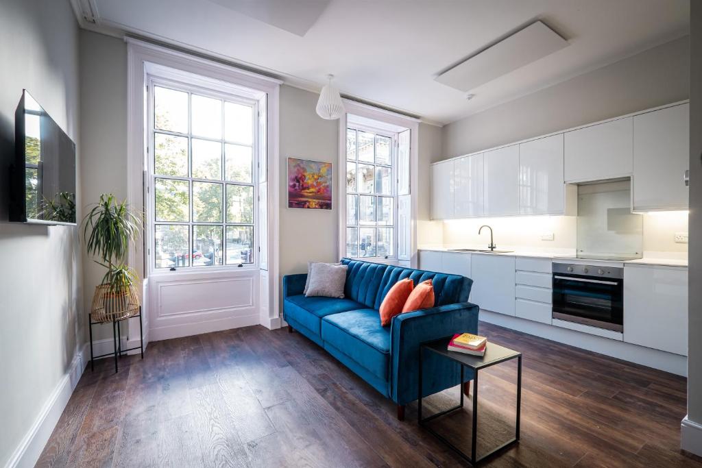 a living room with a blue couch and a kitchen at Dalton Sq Apartment 1 in Lancaster