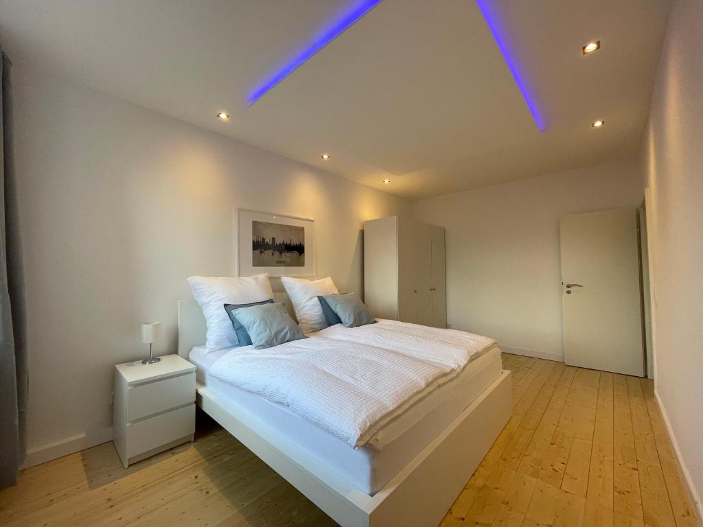 um quarto com uma grande cama branca e luzes azuis em WH Immobilien Design City Appartement Rainshower em Hanôver