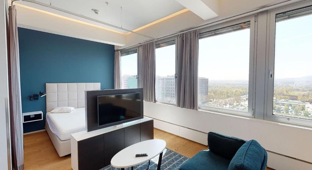 pokój hotelowy z telewizorem, łóżkiem i oknami w obiekcie Key Residences Vienna w Wiedniu