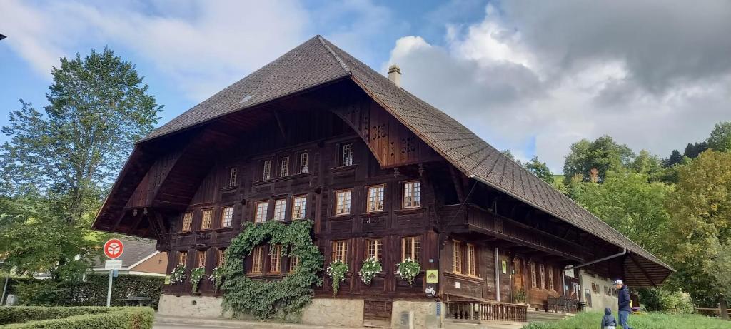 ein großes Holzgebäude mit einem Gameradach in der Unterkunft Emme Lodge in Langnau im Emmental