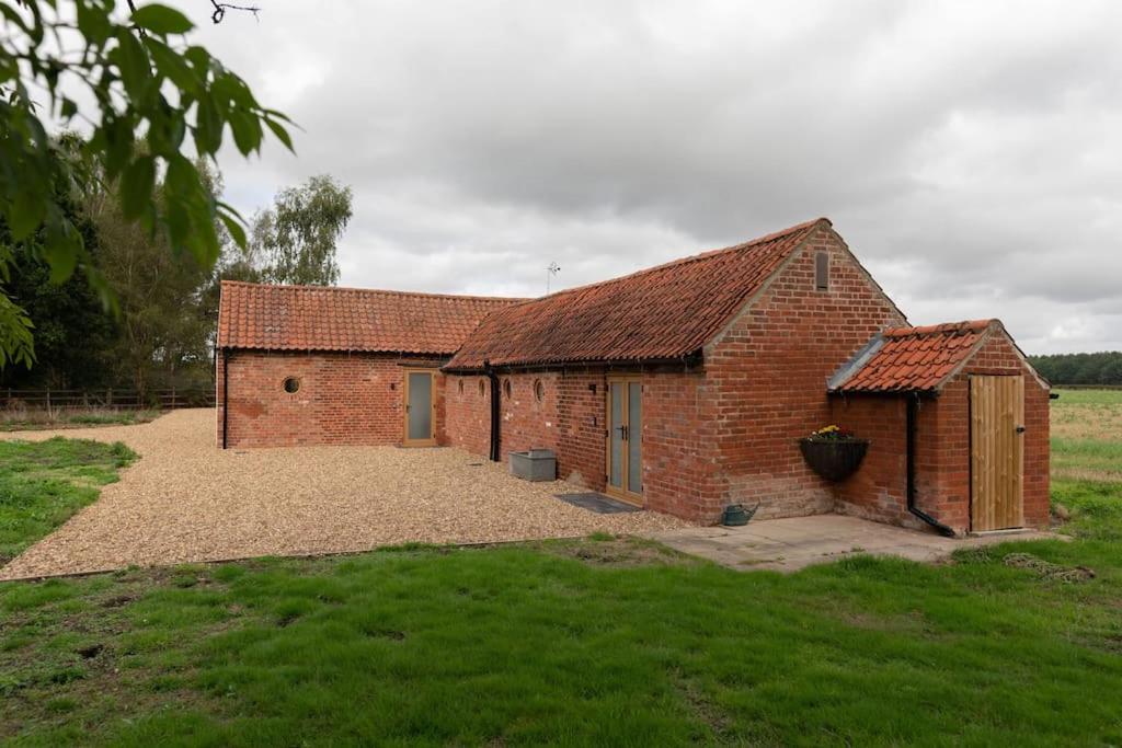 a brick building with a large yard in a field at Beautiful barn conversion surrounded by woodland near Newark Show-ground 