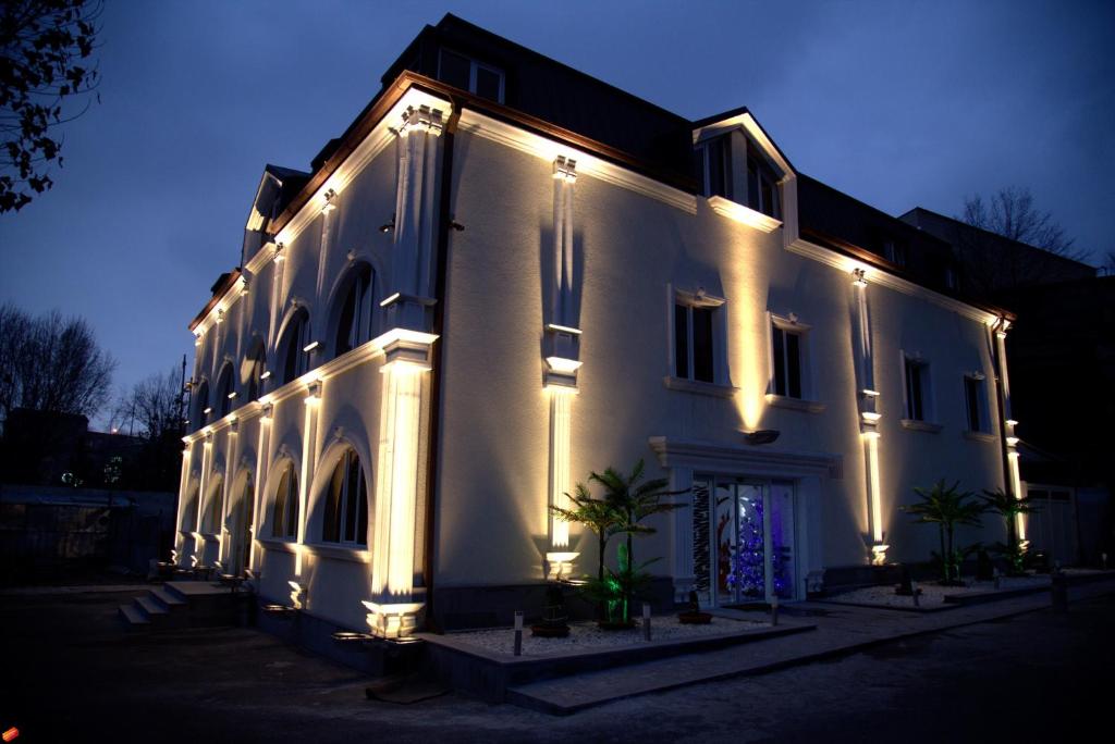 un gran edificio blanco con luces encendidas por la noche en Palma Palace Hotel, en Ereván
