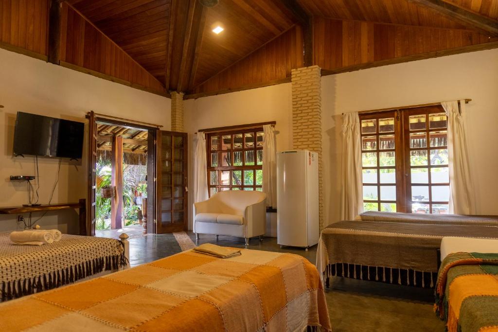 1 dormitorio con 2 camas, TV y silla en Pousada Capitão Gancho, en Barra Grande