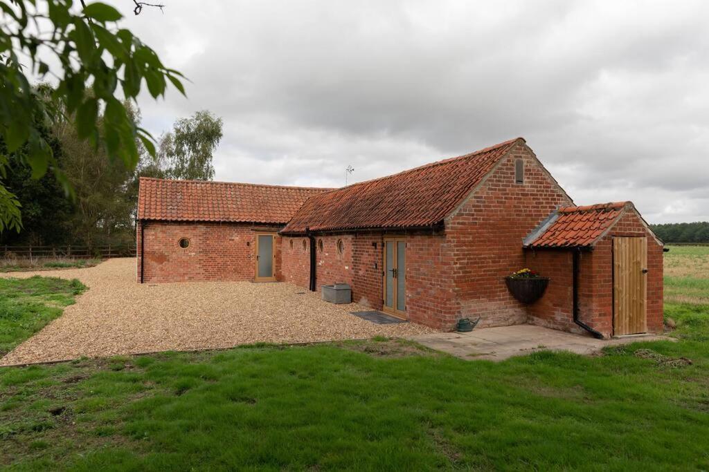 a brick building with a large yard in a field at Lovely 1-bed suite & bathroom in converted barn near Newark Show-Ground 