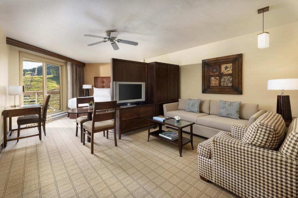 a living room with a couch and a desk with a television at Elevation Hotel & Spa in Crested Butte