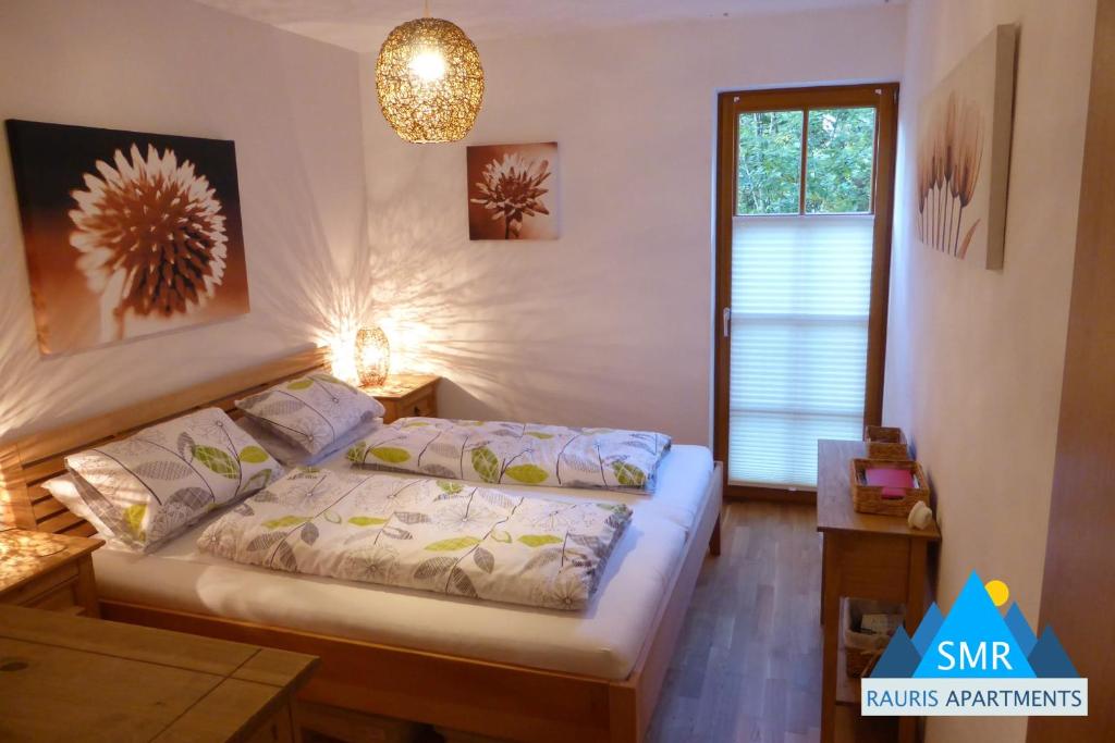 Schlafzimmer mit einem Bett, einem Fenster und einem Kronleuchter in der Unterkunft Daniela 10 by SMR Rauris Apartments - inc Spa and National Summercard - near Gondola in Rauris