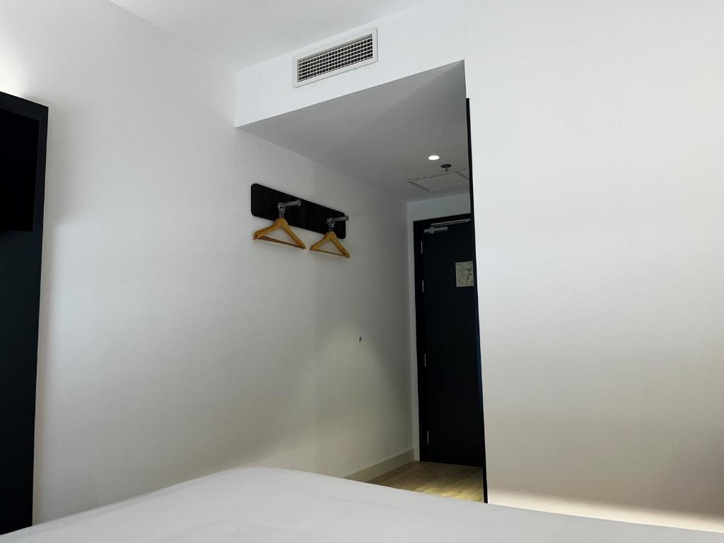 a bedroom with a white wall and a mirror at Hs Madrid Centro Atocha in Madrid