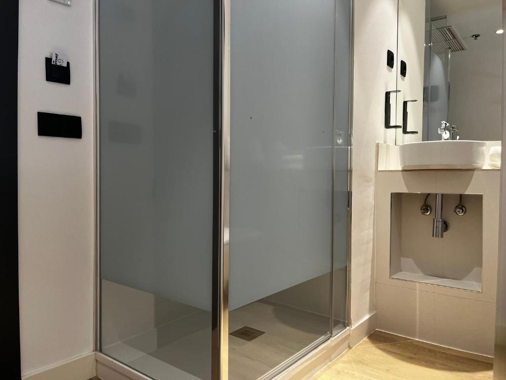 a glass shower in a bathroom with a sink at Hs Madrid Centro Atocha in Madrid