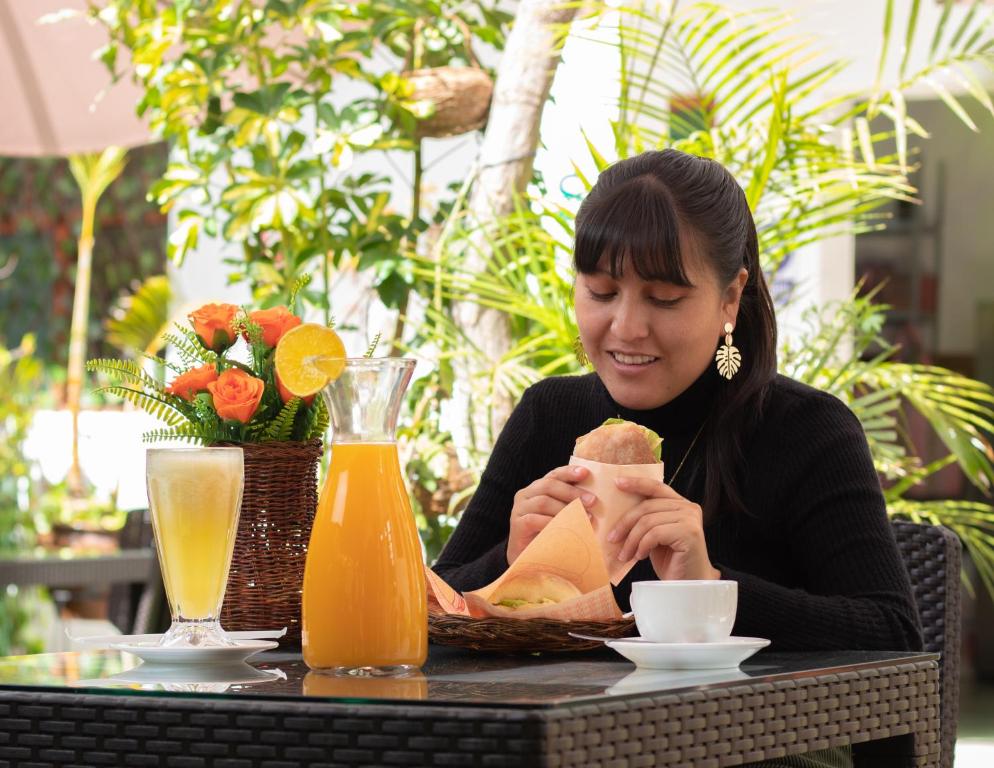 una mujer sentada en una mesa comiendo un sándwich en Hotel Plaza Central, en Ayacucho