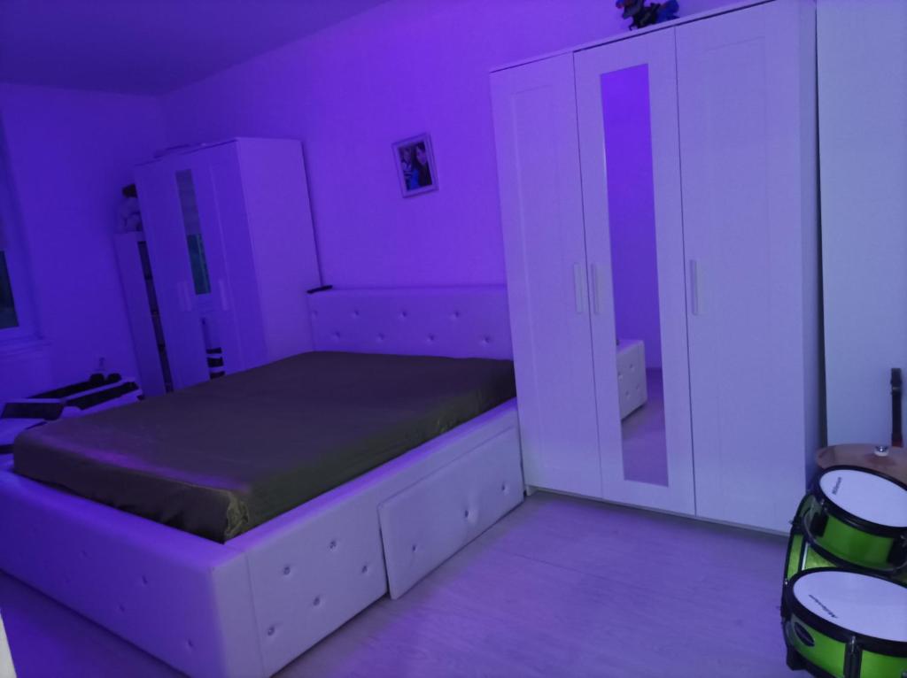 a purple bedroom with a bed and a cabinet at Apartament două camere in Uricani
