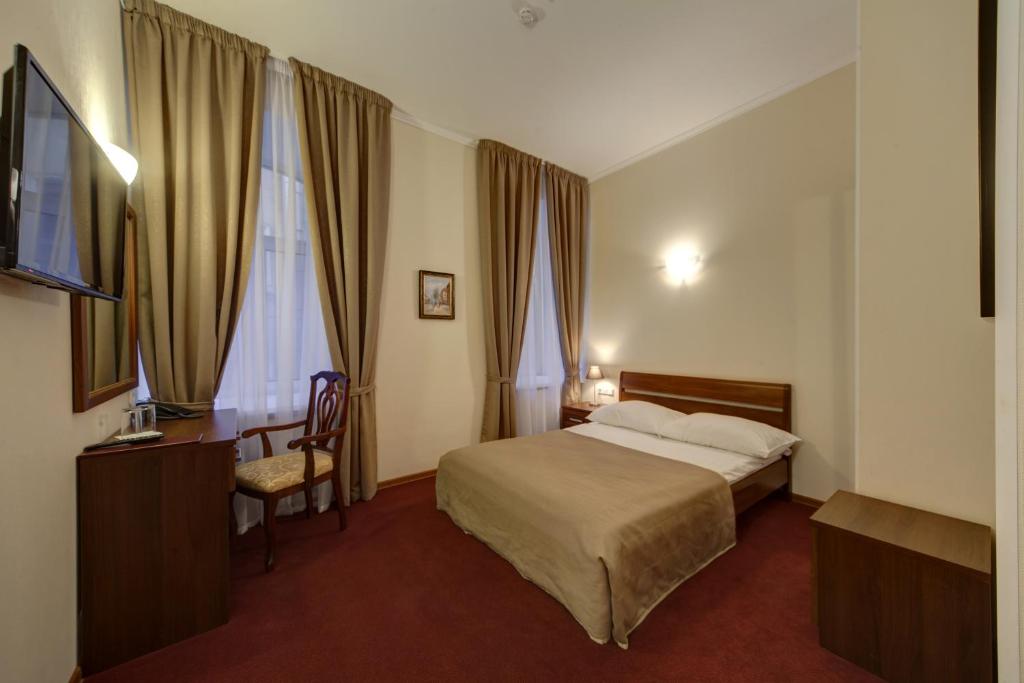 a hotel room with a bed and a desk and window at Sonata on Fontanka in Saint Petersburg