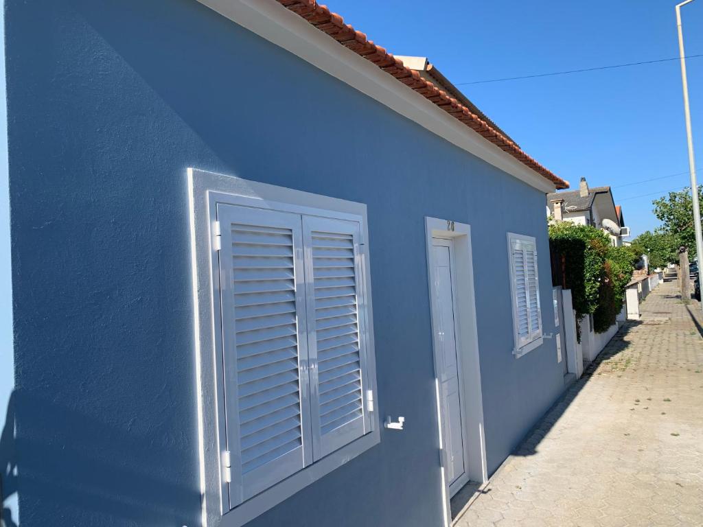 Un bâtiment bleu avec des volets blancs dans l'établissement Torreira Vacation Homes - Sea House, à Torreira