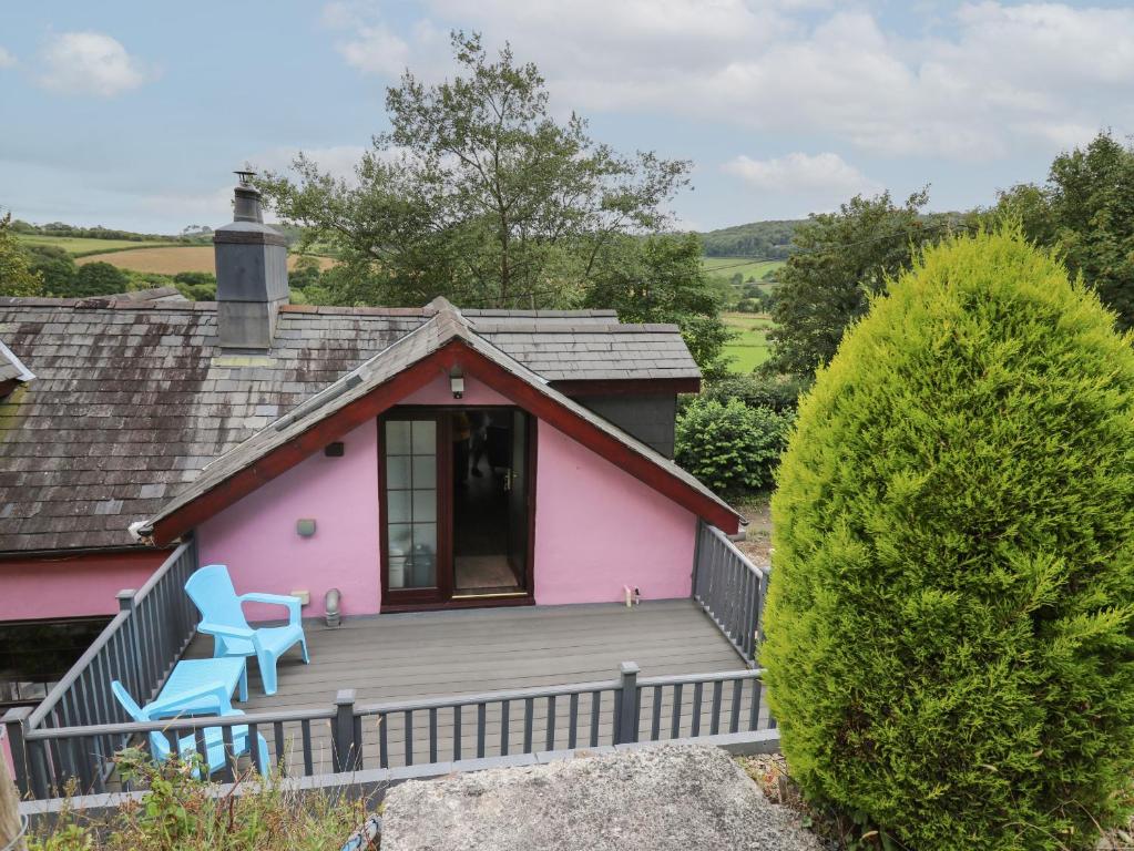 a pink house with two blue chairs on the deck at Tancoed in Aberystwyth