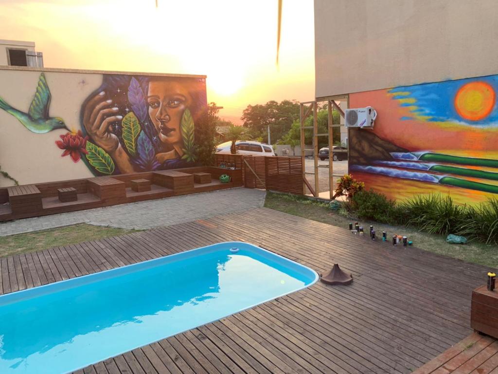 un murale sul lato di un edificio con piscina di Vila do Rosa a Praia do Rosa