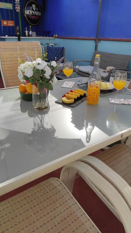 una mesa con un jarrón de flores y vasos de zumo de naranja en Casa Marenga El Palo, en Málaga