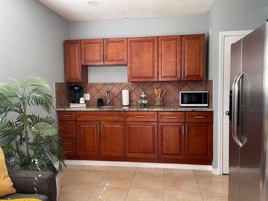 a kitchen with wooden cabinets and a stainless steel refrigerator at The Citrus Guesthouse in Tampa in Tampa