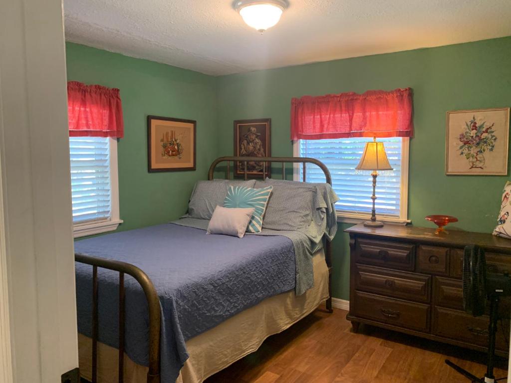 a bedroom with a bed and a dresser and two windows at Nature Coast Inn & Cottages in Inglis
