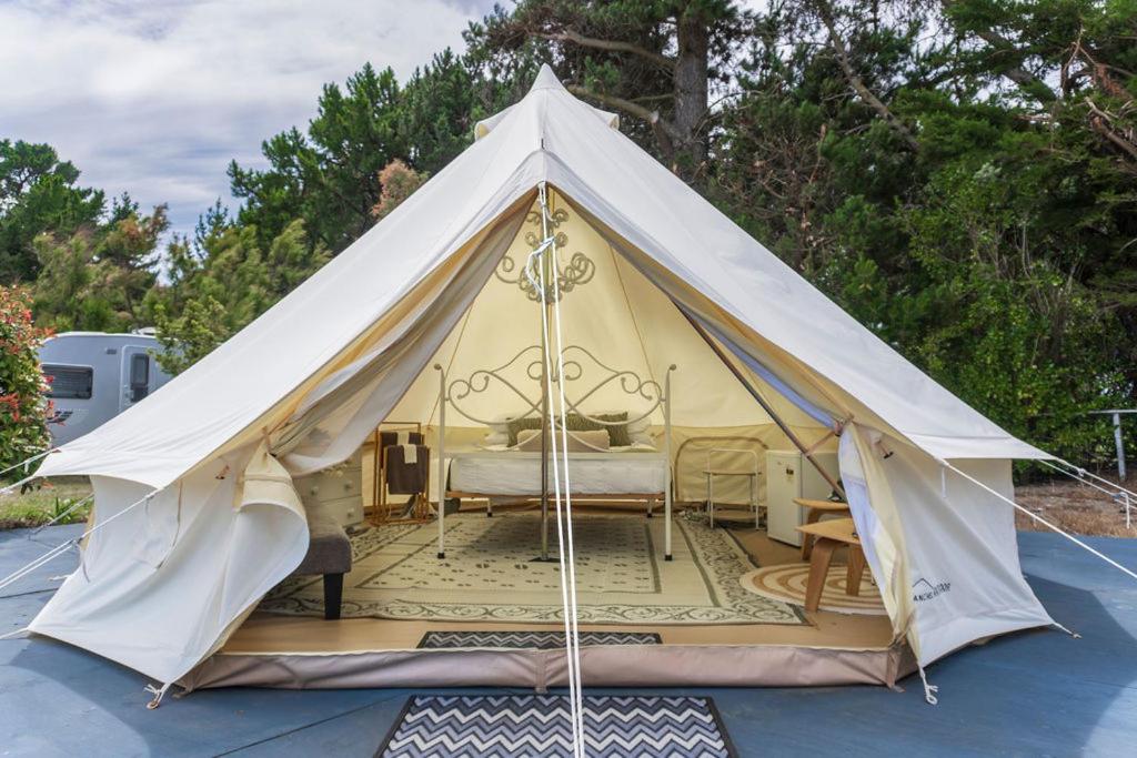 uma grande tenda branca com uma cama em Leithfield Beach Holiday Park em Leithfield