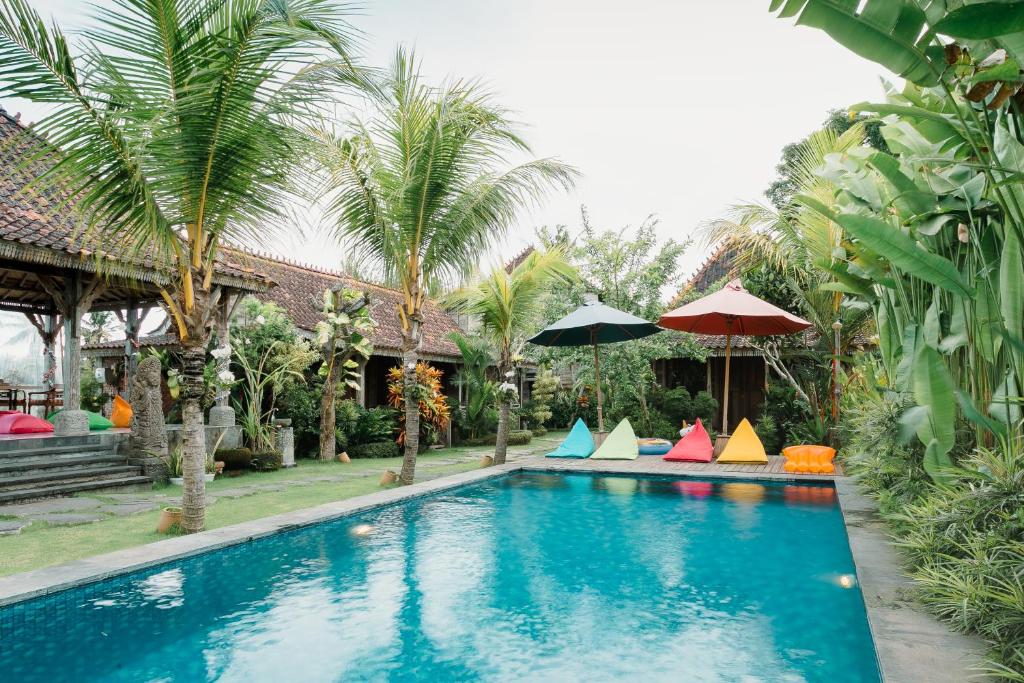 a swimming pool with colorful umbrellas next to a house at Nauna Villa Ubud in Ubud