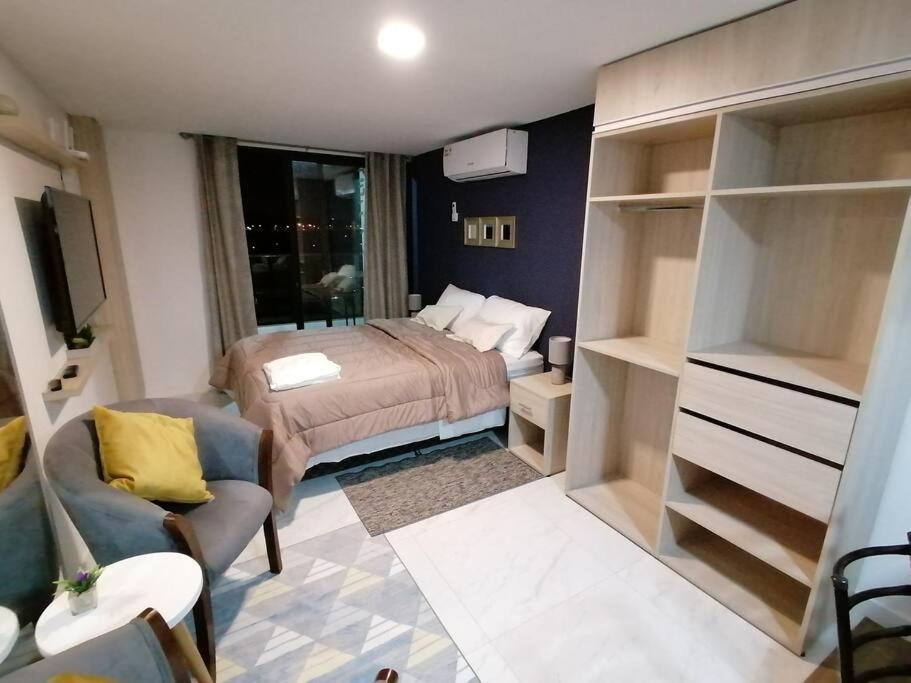 um pequeno quarto com uma cama e um sofá em Hermoso Departamento completamente equipado em Colonia Mariano Roque Alonso