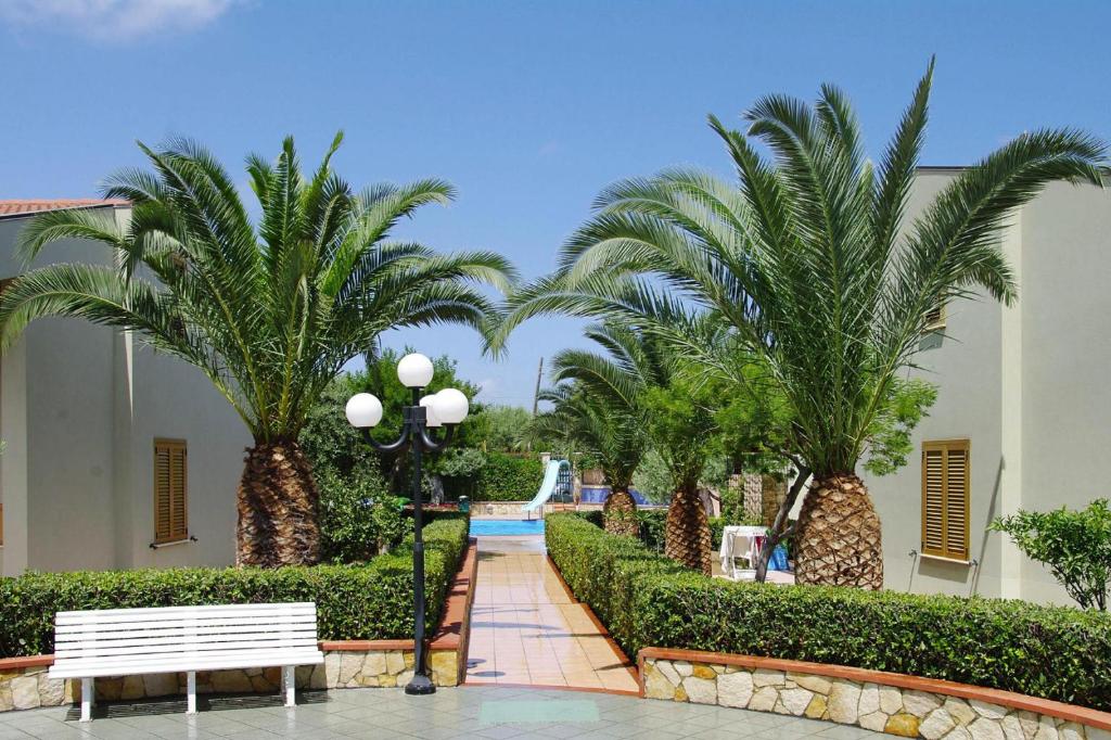 a park with palm trees and a white bench at Residence Fontana Barone, Cefalu in Cefalù