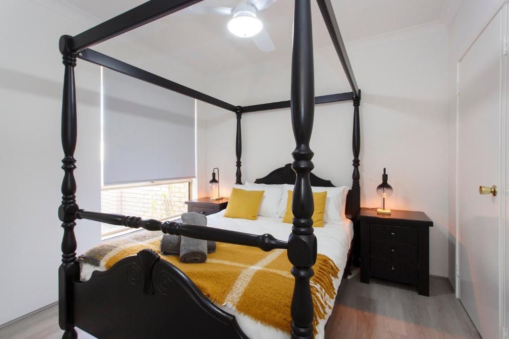 a black four poster bed in a room with a window at Living on Lennard - Pet friendly house close to CBD in Perth