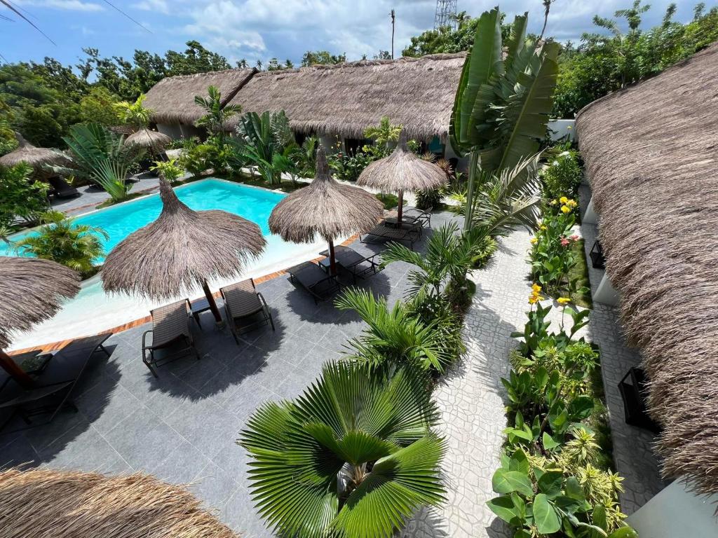 莫阿爾博阿的住宿－Secret paradise moalboal，享有带游泳池和稻草遮阳伞的度假村的空中景致