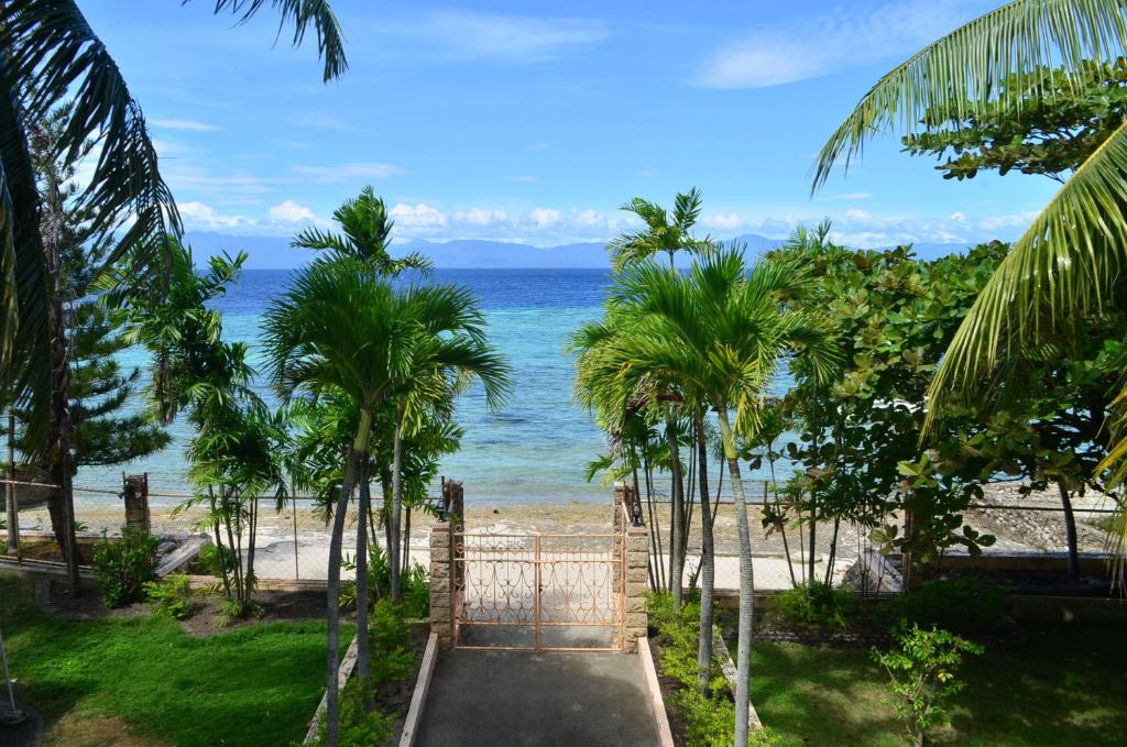 a gate leading to a beach with palm trees at Private beachfront house with ocean view and direct reef access in Moalboal