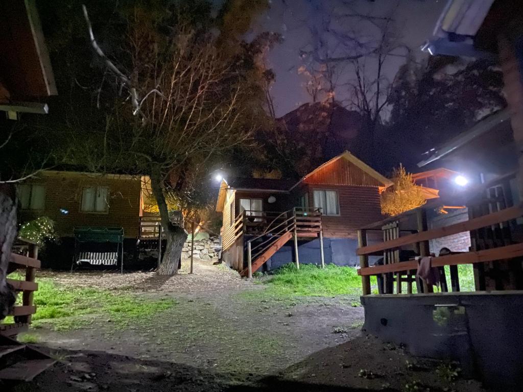 una casa por la noche con una valla y un árbol en Cabañas Between Hills en San Alfonso