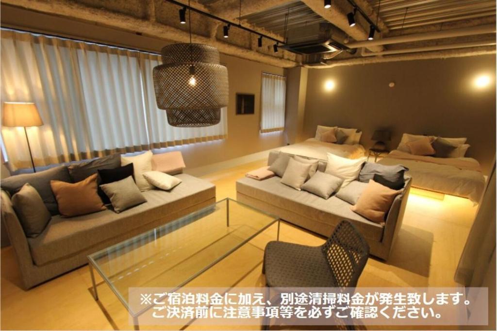 een woonkamer met 2 bedden en een bank bij Nebou Hotel in Osaka