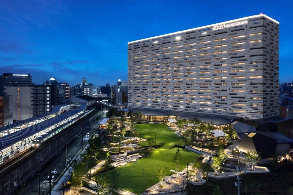 un grand bâtiment avec une pelouse verte devant lui dans l'établissement OMO7 Osaka by Hoshino Resorts, à Osaka