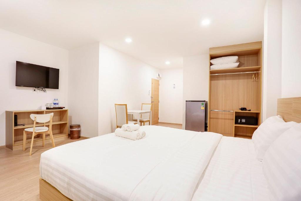 a bedroom with a white bed and a table and chairs at TAKKA Hotel in Bangna