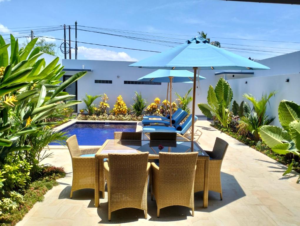 un patio con mesa, sombrilla y piscina en Villa Bintang, en Lovina