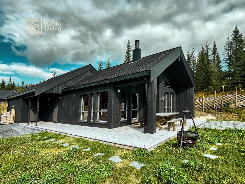 una casa negra con terraza en un campo en Modern unique cabin fantastic location Skeikampen en Svingvoll