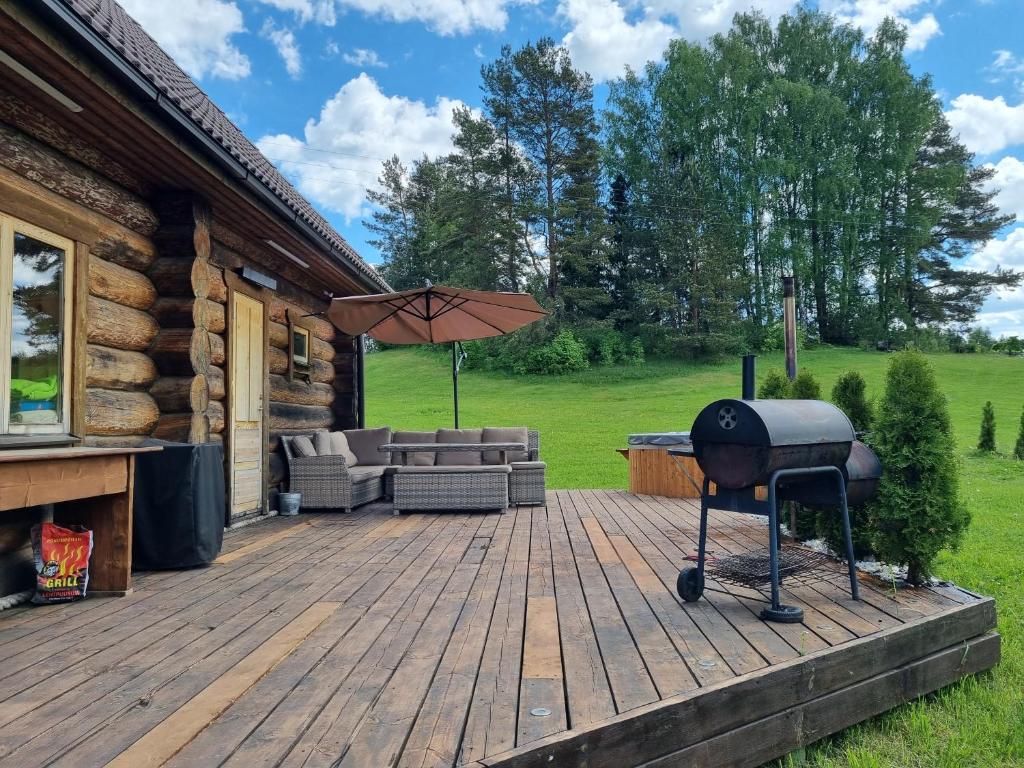 - un barbecue sur une terrasse en bois à côté d'une cabine dans l'établissement Lebola Puhkemaja, à Kasaritsa