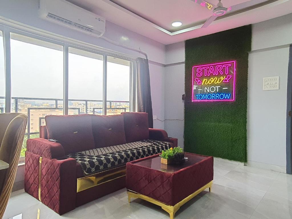 OSI Apartments Andheri East في مومباي: غرفة معيشة مع أريكة وعلامة نيون