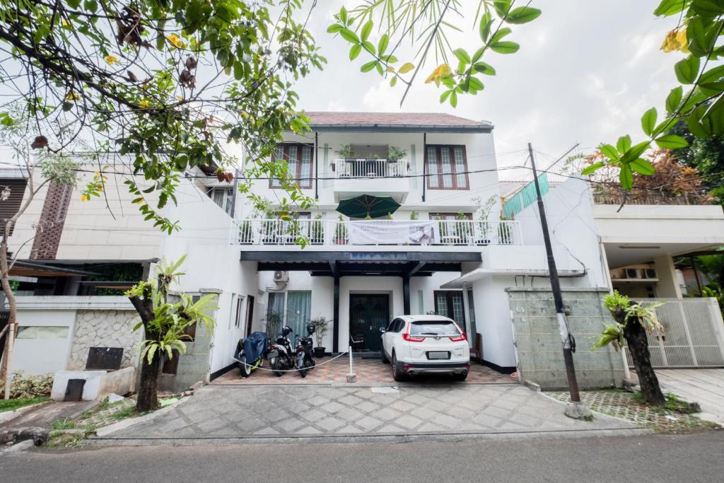 uma casa branca com um carro estacionado em frente dela em Singgahsini Casa D Elok Near PIM 1 em Jakarta