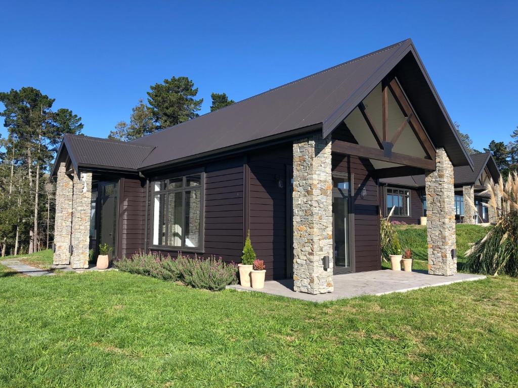 una pequeña casa con techo negro en River View Cottage, en Kahuranaki