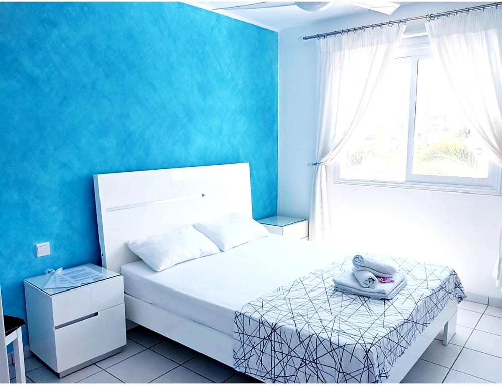 a bedroom with a white bed with a blue wall at My sweet home in Paphos City