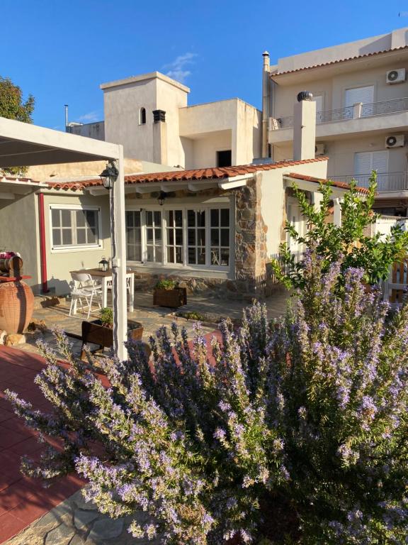 une maison avec un jardin orné de fleurs violettes dans l'établissement Aggelou Apartments, à Spáta