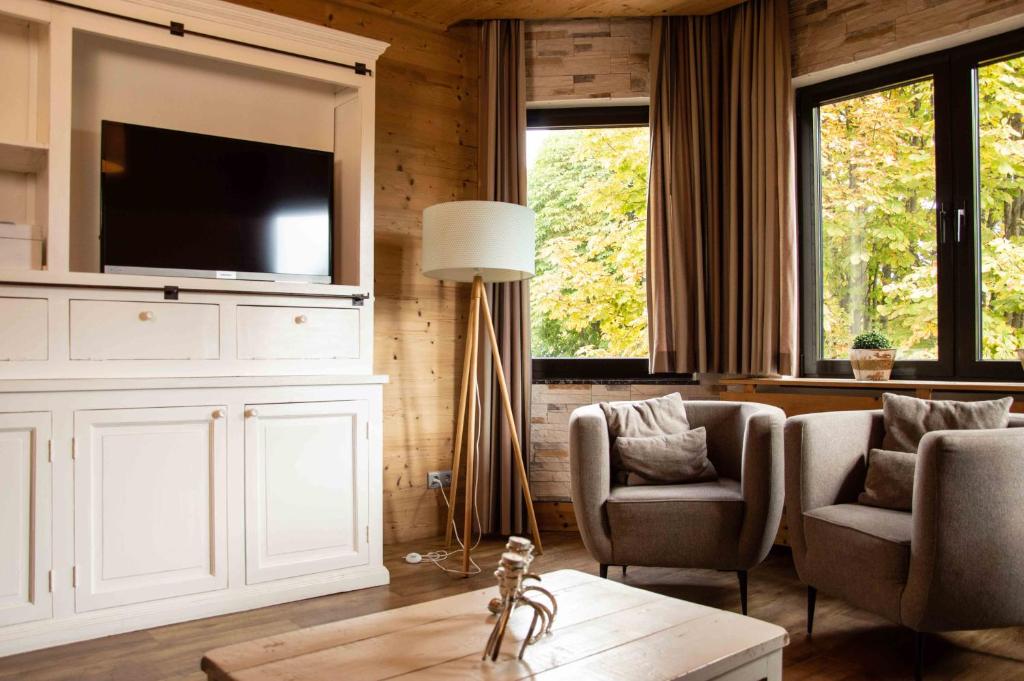 a living room with a tv and two chairs and a table at StrandBerg's Harzchalet in Braunlage