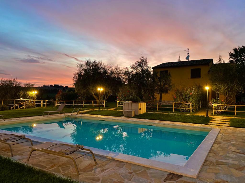 Ostra Vetere的住宿－Montenovo Country House，房屋前带椅子的游泳池