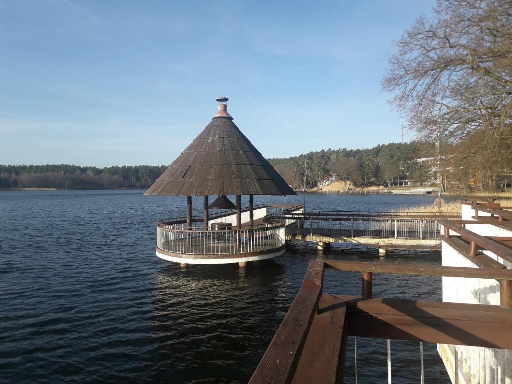 a boat dock with a straw roof on a lake at Apartament Perła 22 Jezioro Pluszne in Mörken