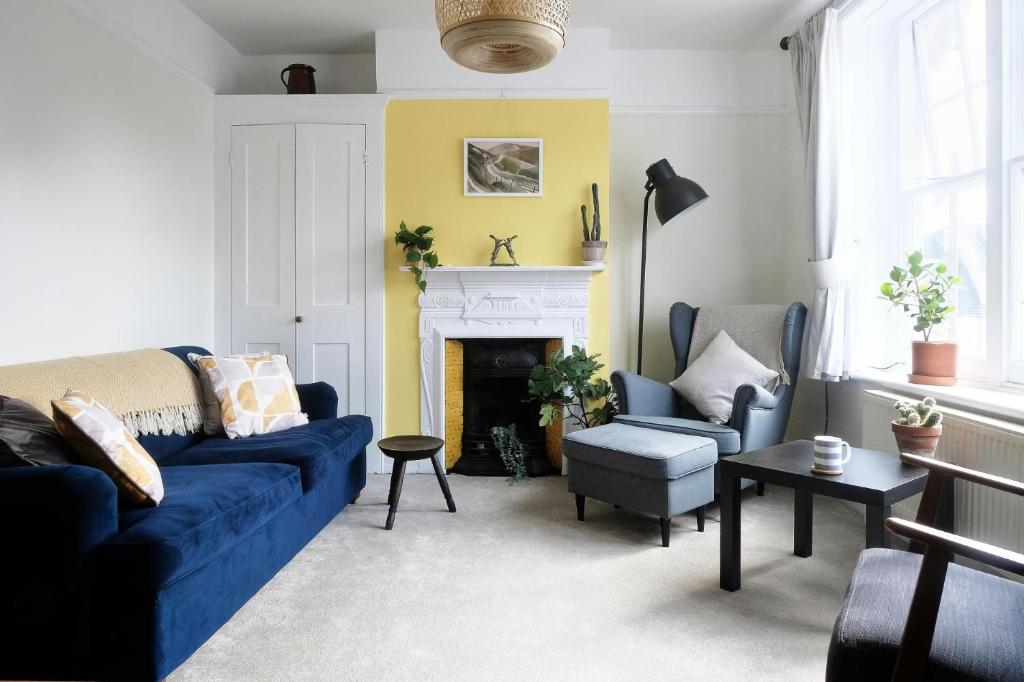 Contemporary 2 Bedroom Flat in Lewes في لويس: غرفة معيشة مع أريكة زرقاء ومدفأة