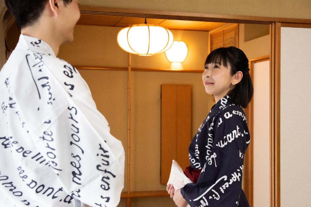 a woman standing next to a man in front of a mirror at Hotel Hagoromo in Shizuoka